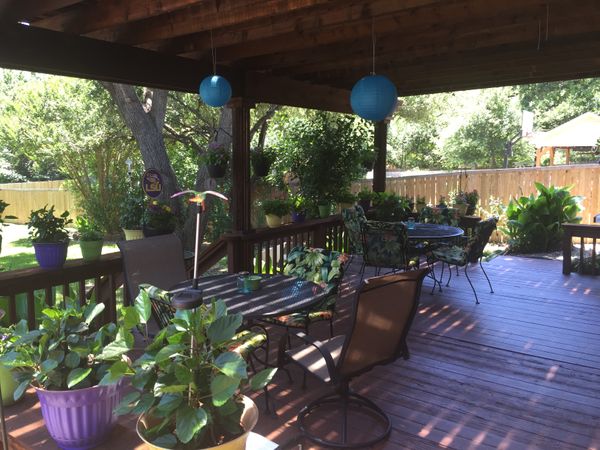 Backyard deck with patio furniture and plants under a pergola
